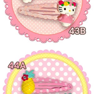 May include: A collection of hair clips with various designs. Includes clips with Hello Kitty, floral, pineapple, and cow motifs. Each clip is set against a decorative background with numbers.