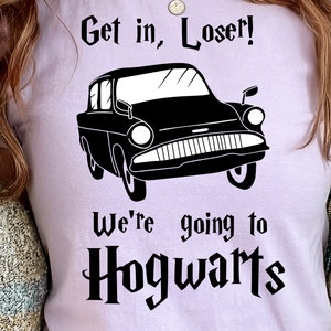 May include: A light purple t-shirt with a black graphic of a car and the text "Get in, Loser! We're going to Hogwarts".