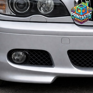 May include: The front bumper of a silver car featuring a circular fog light, a black diamond-patterned grille, and a headlight assembly. A colorful logo in the top right corner displays the text PRINTASTIC WORKSHOP with a 3D printer graphic.