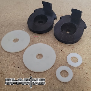 May include: Two black plastic parts with a white plastic tab on each, and four white plastic washers.  The parts are designed to be used in a vehicle.
