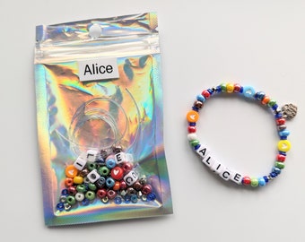 May include: A clear plastic bag with colorful beads, letter beads that spell "Alice", and clear string. A bracelet with colorful beads and letter beads that spell "Alice" is next to the bag.