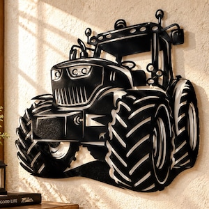 May include: A black metal wall art piece shaped like a tractor, featuring a detailed front grille, large treaded tires, and a cabin structure. The design is cut from a single sheet of metal, creating a silhouette with open spaces between the parts.