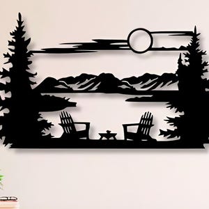 May include: Black metal wall art depicting a lake scene with two chairs, a campfire, and trees. The art is mounted on a white wall above a wooden shelf with books.