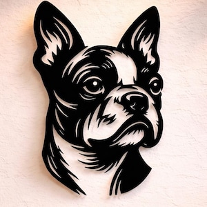 May include: A black and white Boston Terrier dog head wall art. The dog's face is depicted in a minimalist style, with clean lines and a focus on the dog's features. The artwork is mounted on a white wall, adding a modern touch to the room.
