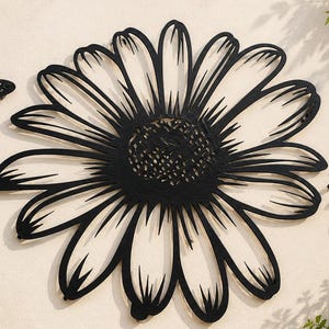 May include: A black metal wall art set featuring a large daisy flower in the center, a butterfly on the left, and a bee on the right. The daisy has long, slender petals and a textured circular center. The butterfly and bee have detailed wing cutouts.