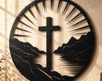 May include: A circular black wall art piece featuring a central cross silhouette. The design includes stylized mountain peaks and a reflective water surface below the cross, with radiating sunburst lines extending toward the outer circular frame.