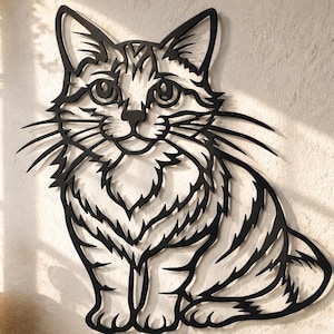 Puede incluir: Una pieza de arte mural de metal negro con forma de gato sentado con texturas de pelaje detalladas y bigotes largos. El gato tiene ojos grandes y orejas puntiagudas, con un diseño recortado que crea una silueta sobre la pared de fondo.
