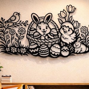 May include: Black laser-cut Easter wall art featuring a bird, bunny, chick, and eggs. The bunny is in a basket, and the art includes floral and leaf details. The artwork is mounted on a cream-colored wall, with a wooden shelf and chair in the foreground.
