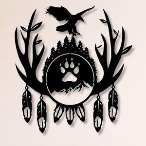 Puede incluir: Arte de pared de metal negro que presenta la silueta de un águila sobre una escena de montaña con una huella de pata. El diseño incluye cornamentas, un bosque y plumas colgantes, creando una estética rústica inspirada en la naturaleza. Ideal para un toque natural.