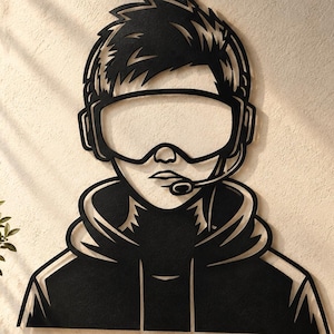 May include: A black metal wall art piece depicting a stylized silhouette of a person wearing a hooded sweatshirt, large gaming headset, and goggles with a microphone attachment extending toward the mouth, featuring sharp, clean-cut geometric lines.