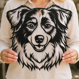 May include: A black metal wall art piece featuring a detailed cutout silhouette of an Australian Shepherd dog head. The design showcases the dog's facial features, including pointed ears, expressive eyes, a nose, and a textured fur pattern.