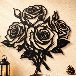 May include: A black metal wall art piece featuring a detailed cutout design of a bouquet of roses with leaves and buds. The artwork displays intricate lines and shapes that form the floral arrangement, creating a bold silhouette against the wall.