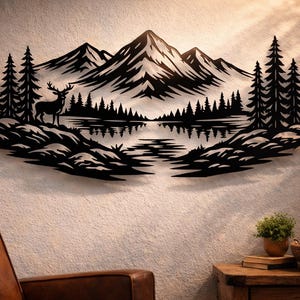 May include: Black metal wall art depicting a mountain landscape with a lake, trees, and a deer. The artwork is mounted on a textured wall. The scene includes a deer standing near the lake, with trees and mountains in the background.