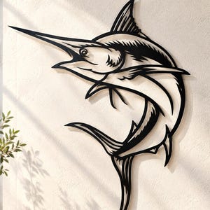 May include: A black metal wall art piece shaped like a marlin fish in a leaping pose. The design features cut-out details that define the fish's body, fins, and long bill, creating a silhouette effect against the light-colored wall surface.