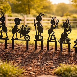 Puede incluir: Estacas de jardín de metal negro que representan hormigas de dibujos animados. Las estacas muestran hormigas cortando el césped, usando herramientas y relajándose. Ideal para decorar un jardín.