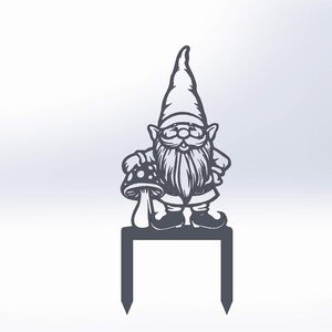 May include: A dark grey metal garden stake featuring a gnome holding a mushroom. The gnome has a long beard and a pointed hat. It is standing on a rectangular base with two pointed stakes for the garden.