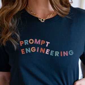 May include: A black t-shirt with the text "PROMPT ENGINEERING" in colorful letters. The letters are in a diagonal pattern, with the word "PROMPT" at the top and "ENGINEERING" at the bottom.