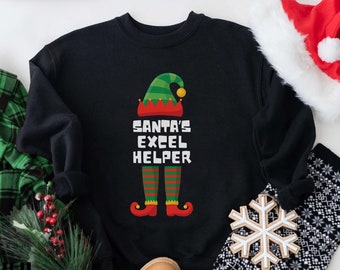 Puede incluir: Sudadera negra con un diseño de elfo y el texto "SANTA'S EXCEL HELPER". El diseño del elfo incluye un gorro verde, piernas a rayas rojas y verdes y zapatos rojos. Una sudadera con temática navideña.