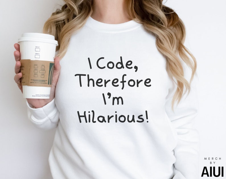 K&ouml;nnte beinhalten: Wei&szlig;er Pullover mit dem Aufdruck "I Code, Therefore I'm Hilarious!" auf der Vorderseite. Eine Person h&auml;lt eine Kaffeetasse in der linken Hand.