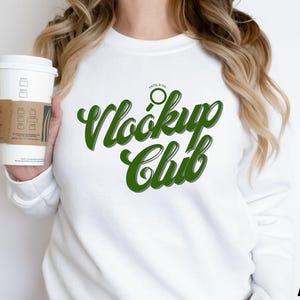 May include: White sweatshirt with green text that reads "Look Up Club" and a small magnifying glass icon above the text.