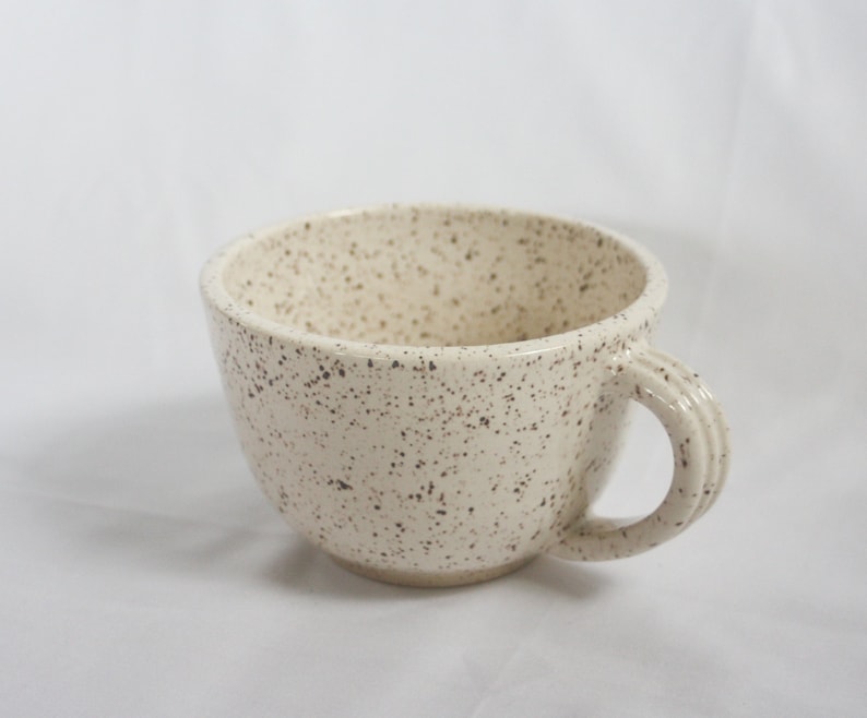 white ceramic teacup with dark brown speckled glaze