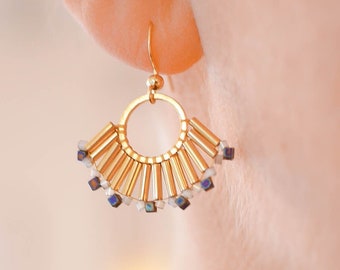 May include: Gold-tone fan-shaped earrings with a small hoop and a cluster of small, colorful beads. The earrings have a geometric design with vertical gold bars and are shown on a person's ear.