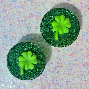 May include: Two green glitter resin cabochons with a green four-leaf clover design.