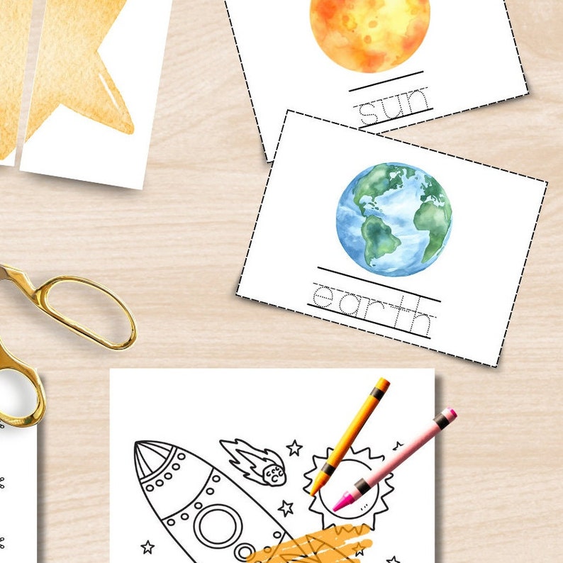 May include: Watercolour illustrations of the sun and Earth on white cards with the words "sun" and "earth" below. A rocket ship colouring page with crayons and a star-shaped cutout are also visible. Educational theme.