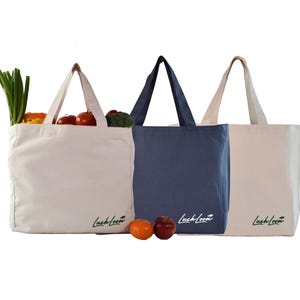 Peut inclure: Trois sacs cabas réutilisables, un blanc, un bleu et un en toile naturelle. Chaque sac porte l'inscription "Lush Loom" imprimée en vert sur le devant.
