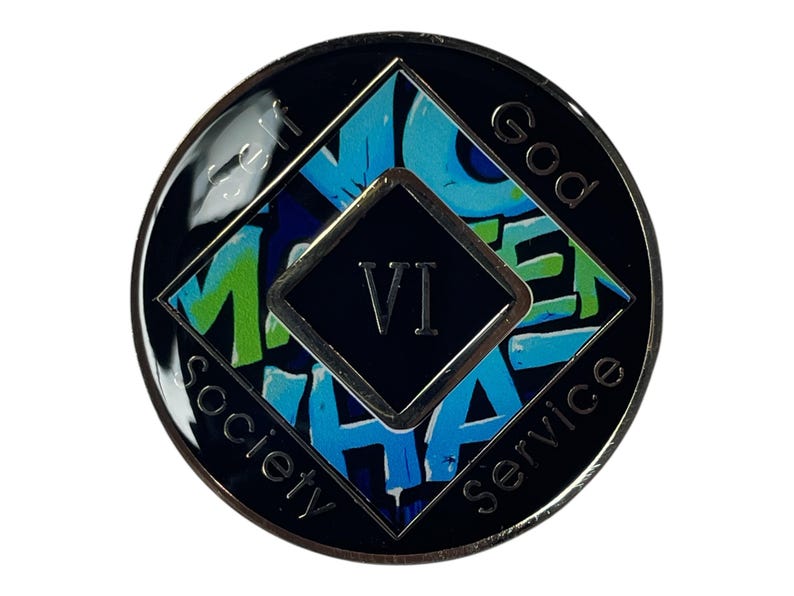 A black and silver coin with a blue, green, and white design. The coin has a black square in the center with the number 'VI' in white text. The coin has the words 'God', 'Self', 'Service', 'Society', around the outside of the coin.