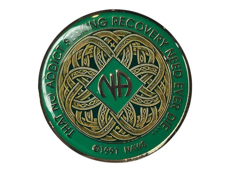Narcotics Anonymous Celtic knot recovery medallion with green enamel and intricate gold knotwork design, featuring the NA logo in the center and the phrase “That No Addict Seeking Recovery Need Ever Die,” symbolizing unity, connection, and spiritual growth in recovery.