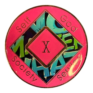 The reverse side of a pink recovery medallion showing the roman numeral X and Self, God, Society, and Service.