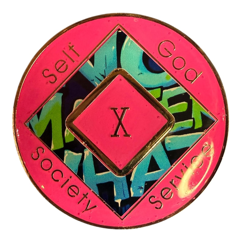 The reverse side of a pink recovery medallion showing the roman numeral X and Self, God, Society, and Service.