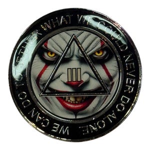 May include: A round, silver-colored coin featuring a clown face with red accents and yellow eyes within a triangle. The coin has the text "TOGETHER WHAT WE COULD NEVER DO ALONE. WE CAN DO" around the edge.