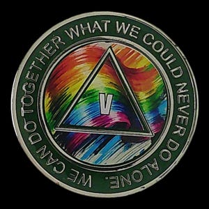 May include: A round metal sobriety coin featuring a dark green outer border with the text WE CAN DO TOGETHER WHAT WE COULD NEVER DO ALONE. The center displays a triangle with the Roman numeral V, set against a vibrant, multi-colored rainbow background.