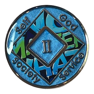 Blue Narcotics Anonymous recovery medallion with a diamond center showing the Roman numeral II. Surrounding words read ‘Self,’ ‘God,’ ‘Society,’ and ‘Service,’ with graffiti-style text ‘No Matter What’ in the background.