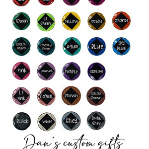 May include: A color chart featuring twenty-four circular medallions in various colors, each with a central black diamond and the words Self, God, and Service. The text Dan's custom gifts Medallion color chart and *colors may vary slightly appear below.