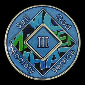The reverse side of a blue recovery medallion showing the roman numeral III and Self, God, Society, and Service.