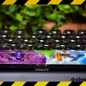 May include: A purple, green, and blue resin keycap with a Pokemon theme. The keycap features a Gengar, a Squirtle, and a Pikachu.