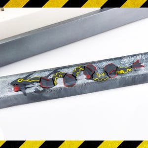 May include: A grey and white resin keycap with a red and yellow dragon design.