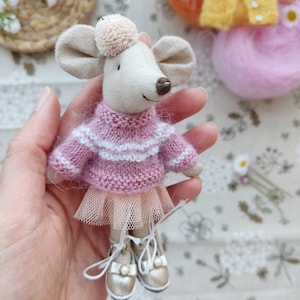 May include: A small, handmade mouse doll wearing a pink and white striped sweater, a tulle skirt, and gold shoes. The doll is being held in a hand.