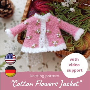 Può includere: Una giacca lavorata a maglia rosa e bianca con dettagli floreali. La giacca presenta colletto, polsini e bordi bianchi ed è decorata con piccoli fiori bianchi. Il testo "Cotton Flowers Jacket" è visibile. L'immagine include anche le bandiere americana e tedesca.