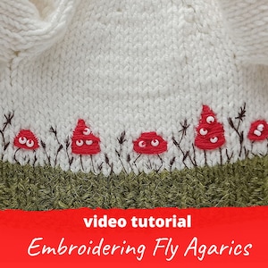 Könnte beinhalten: Weißer Strickstoff mit einer Reihe roter gestickter Pilze mit weißen Punkten. Die Pilze befinden sich auf einem grünen Strickstoff-Hintergrund. Der Text "Video-Tutorial Sticken von Fliegenpilzen" befindet sich am unteren Rand des Bildes.