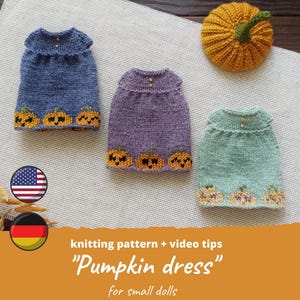 May include: Three knitted doll dresses in blue, purple, and mint green, each with a pumpkin design at the hem. A knitted pumpkin sits nearby. The image includes the text "Pumpkin dress" and "for small dolls".