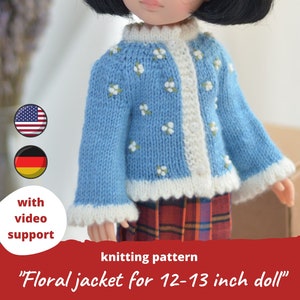 May include: A light blue knitted floral jacket for a doll, with white trim and small white flower details. The jacket is designed for a 12-13 inch doll. The text on the image says "Floral jacket for 12-13 inch doll" and "with video support".
