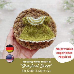 Puede incluir: Un vestido verde tejido con detalles blancos, exhibido sobre un posavasos tejido. El vestido es una miniatura, probablemente para una muñeca o un niño. El texto dice "Storybook Dress" y "Big Sister & Mom size".