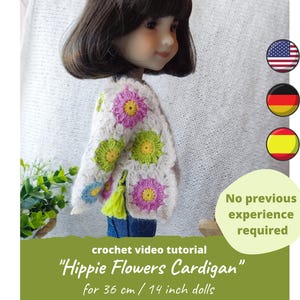 May include: A doll wearing a crocheted white cardigan with colorful flower appliques. The cardigan is designed for 14-inch dolls. The image includes text that reads "Hippie Flowers Cardigan" and "No previous experience required."