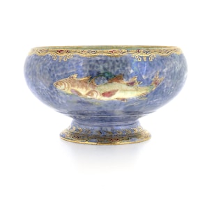May include: A blue ceramic bowl with a fish design. The bowl has a textured surface and a decorative gold rim. The fish are depicted in shades of brown, green, and red. The bowl is approximately 6 inches in diameter.