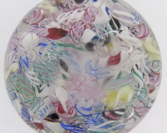 May include: A clear glass paperweight with swirls of white, pink, blue, green, and yellow glass.