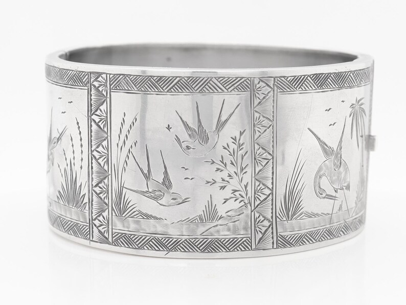 Puede incluir: Pulsera de plata con un dise&ntilde;o grabado de p&aacute;jaros y follaje. La pulsera tiene un patr&oacute;n geom&eacute;trico alrededor del borde.
